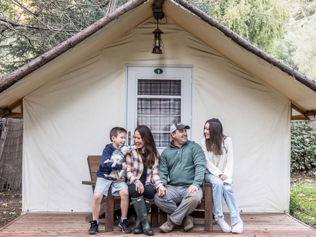 family hanging outside their tent at rivers bend resort in forestville