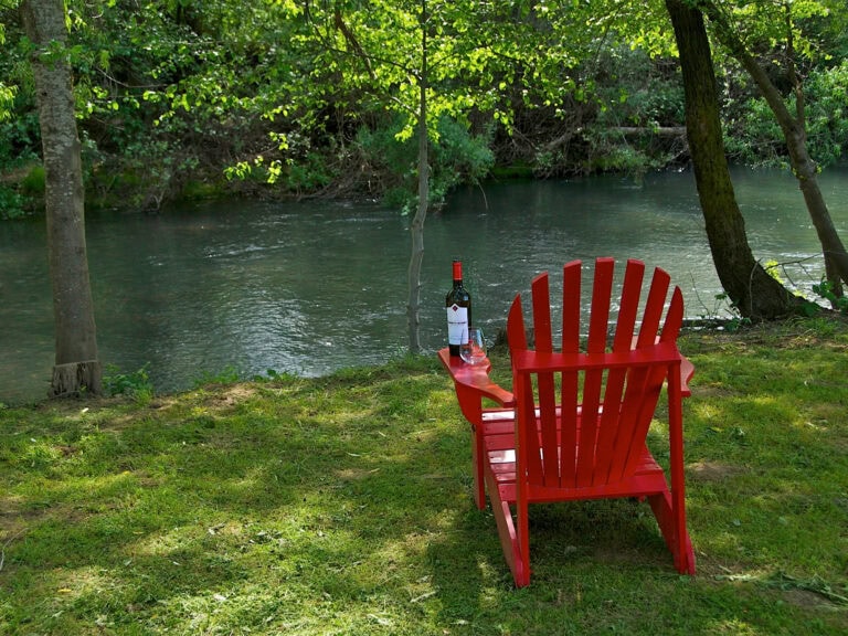 red chair along the river with a bottle of wine at truett hurst winery in healdsburg