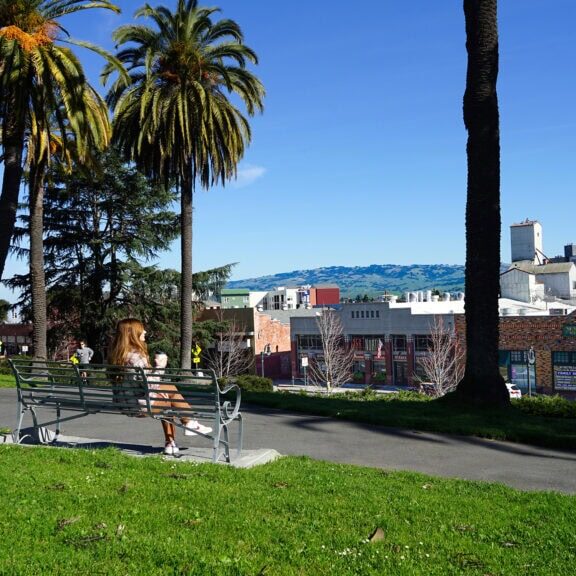 a person enjoying a cup of coffee on a bench at a park in downtown petaluma